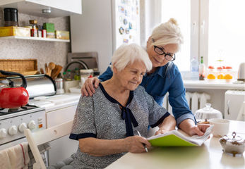 An elderly woman and a younger woman working on paperwork together