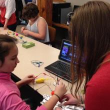 Student and instructor use materials to create a keypad to play Pac-Man.