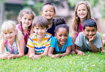 A group of young children laying on the grass outdoors